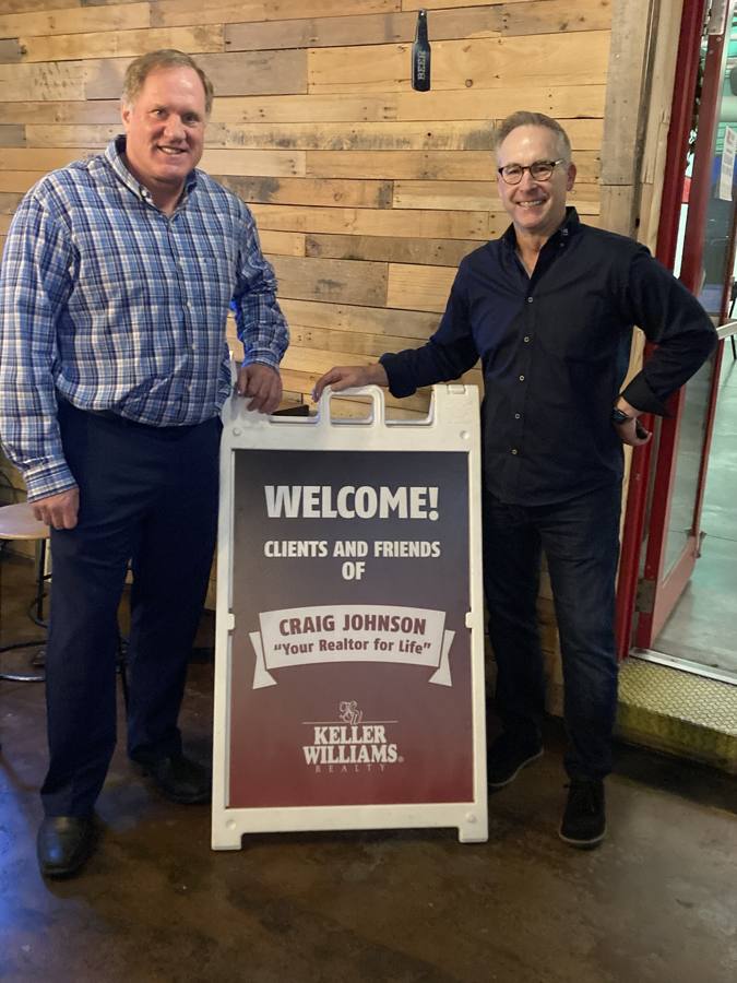 Craig and a guest beside the welcome sign at a past event